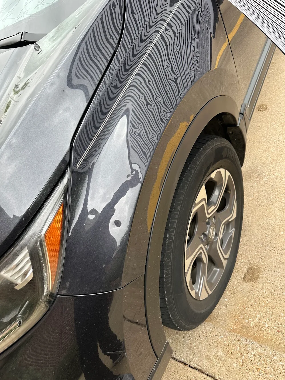 Straight reflected lines distorting across a dented vehicle fender, revealing hail impacts