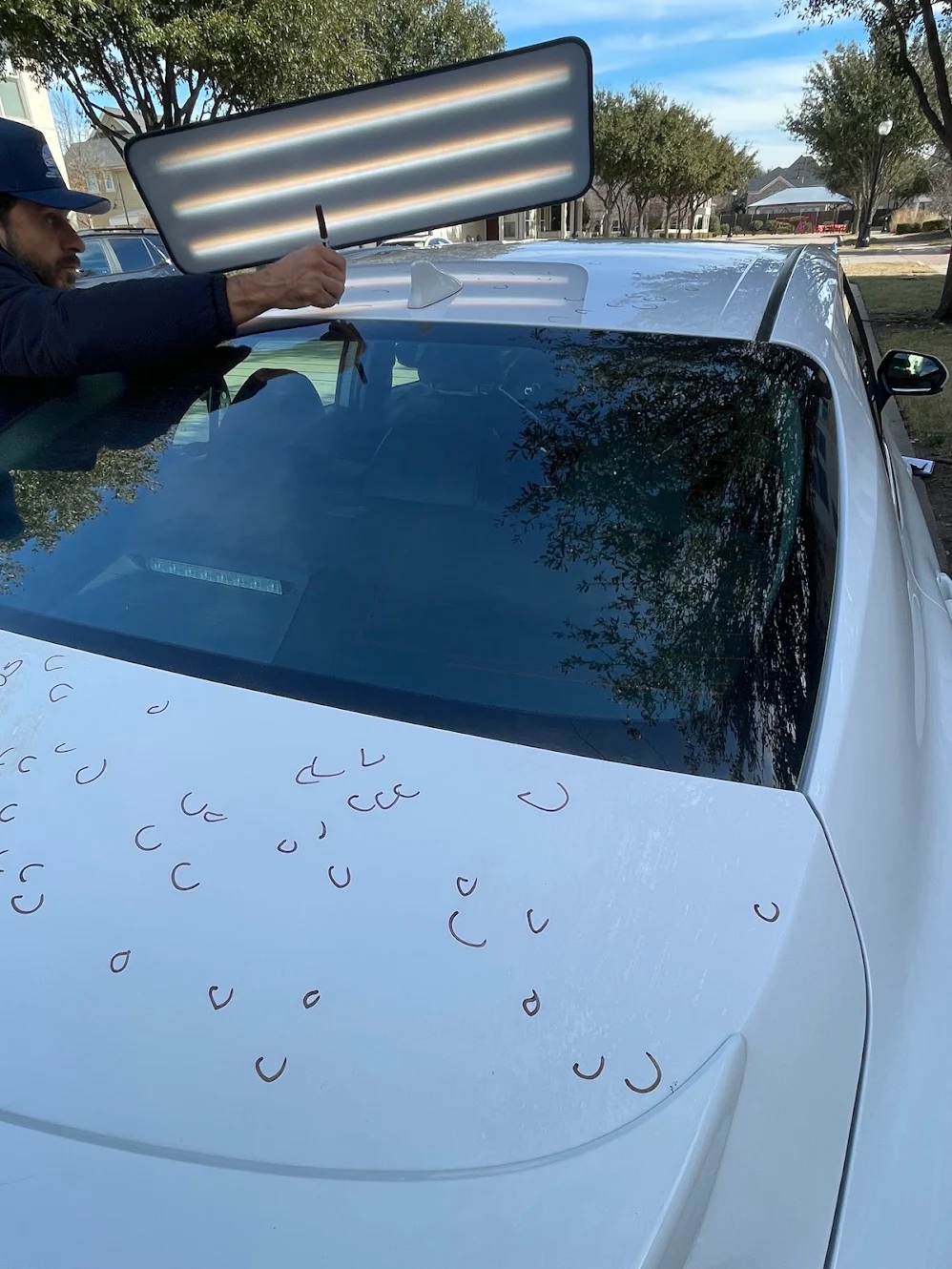 Hail damage on a customer vehicle hood, photographed under a raking inspection light