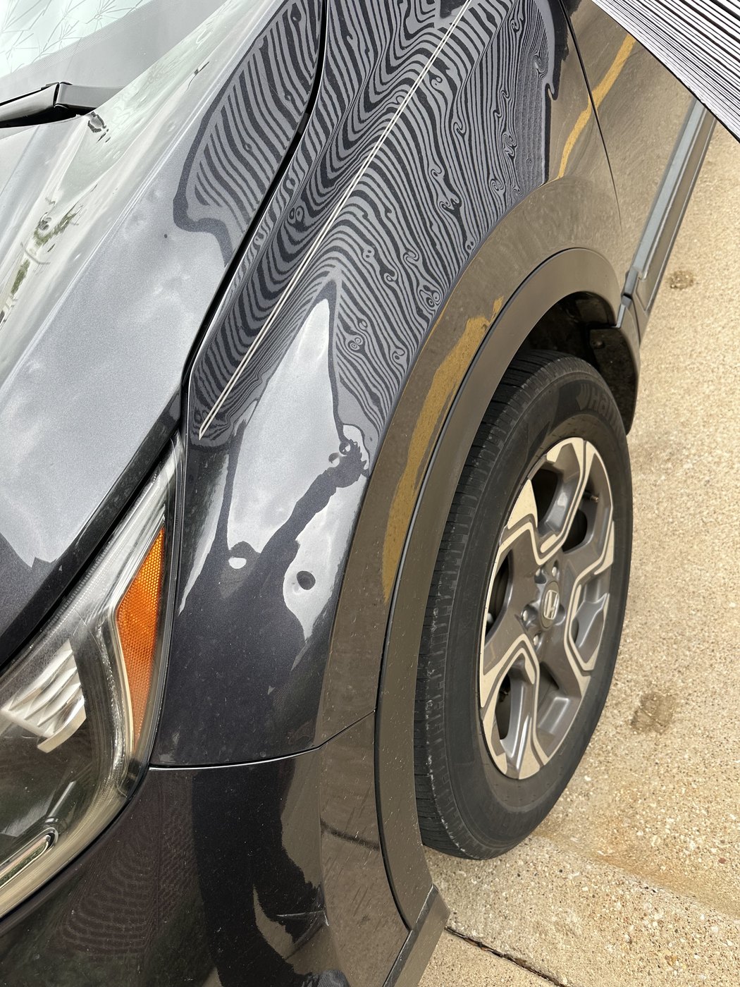 Straight lines reflected across a vehicle fender bending around each hail impact
